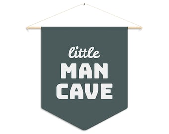 Peut inclure: Une bannière en forme de pennant gris foncé avec le texte "little man cave" en lettres blanches.
