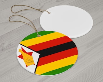 May include: Two round ceramic ornaments. One features the flag of Zimbabwe with green, yellow, red, and black stripes, and a white emblem with a bird and star. The other ornament is plain white. Both have brown string loops for hanging.