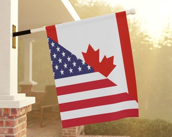 May include: A red, white, and blue American flag is displayed next to a Canadian flag with a red maple leaf on a white background. The flags are hanging from a white pole attached to a house.