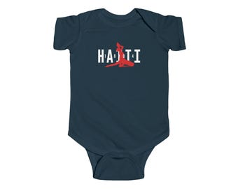 May include: A dark navy blue short-sleeve baby bodysuit featuring a white graphic that spells HAITI with the numbers 1804. The letter I is replaced by a red silhouette of a person in a kneeling pose, centered on the chest of the garment.