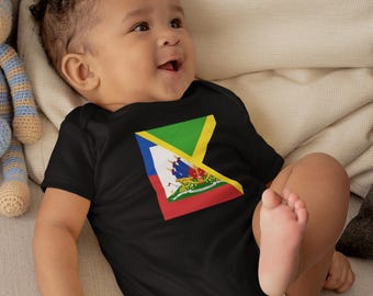 May include: A black baby bodysuit featuring the Haitian flag design in the center. The flag design includes a blue and red section, a green triangle, and a yellow X-shaped border. The baby is lying on a cream-colored blanket.