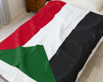 May include: A white bedspread with a design of the Sudanese flag. The flag features a red stripe, a white stripe, a black stripe, and a green triangle. The bedspread is on a bed with a wooden frame.