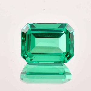 May include: A vibrant green emerald gemstone cut in an emerald shape. The gemstone is faceted and has a high level of clarity.