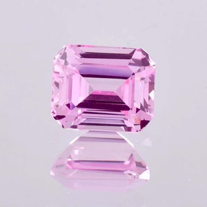 May include: A pink emerald cut gemstone with a high polish.