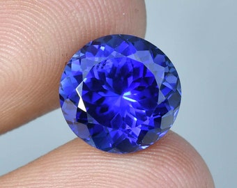 May include: A deep blue gemstone with a round cut and a faceted surface.