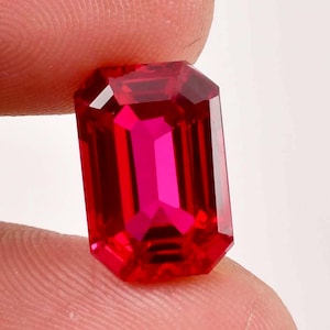 Könnte beinhalten: Ein leuchtend roter Smaragdschliff-Edelstein mit hohem Glanz.