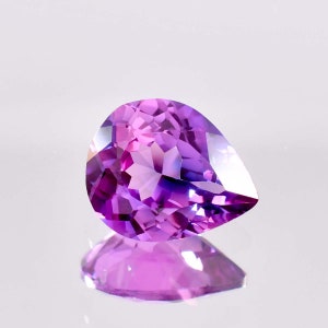 May include: A pear-shaped amethyst gemstone with a deep purple hue. The gemstone is faceted and has a high degree of brilliance.