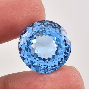 May include: A round, faceted, light blue gemstone with a star-shaped pattern in the center.