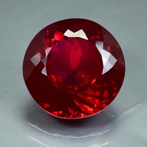 Könnte beinhalten: Ein tiefroter Edelstein mit runder Form und hohem Glanz. Der Stein ist facettiert und hat einen brillanten Glanz.