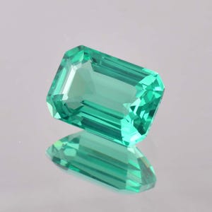 Op de afbeelding: Een levendige groene smaragd edelsteen geslepen in een smaragd vorm. De edelsteen is gefacetteerd en heeft een hoge mate van helderheid.