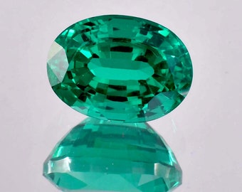 May include: A vibrant green oval-shaped gemstone with a faceted cut. The gemstone is reflecting light, showcasing its brilliance.