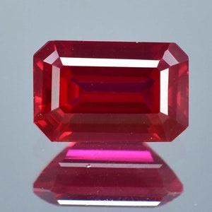 Peut inclure: Une pierre précieuse rouge foncé de taille émeraude rectangulaire. La pierre précieuse est facetée et a un haut poli.