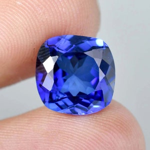 May include: A deep blue cushion-cut gemstone with a faceted surface.