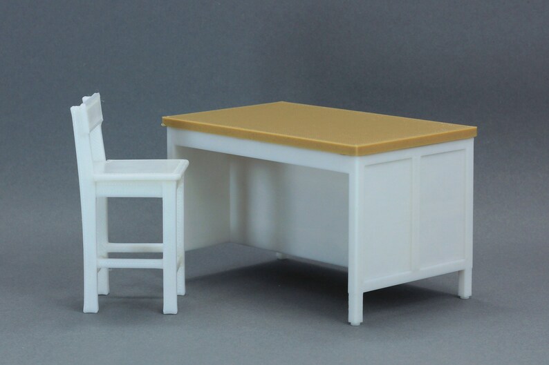 Op de afbeelding: Een wit bureau met een lichtbruin blad en een witte stoel. Het bureau heeft een eenvoudig ontwerp met een rechthoekig blad en een enkele lade. De stoel heeft een eenvoudig ontwerp met een rechthoekige zitting en een rugleuning.