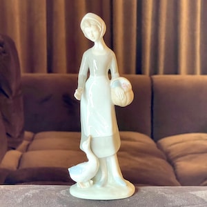 Vintage girl figurine with basket and duck or goose figurine