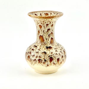 May include: A ceramic vase with a speckled pattern in shades of brown and cream. The vase has a rounded base, a slender neck, and a flared rim. The speckled design covers the entire surface of the vase.