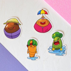 Op de afbeelding: Vier kleurrijke cartoonstickers met antropomorfe groenten. Een bruine aardappel met een gele hoed en paarse jas, een ui met een regenboogparaplu, een wortel en een groene groente zijn afgebeeld. De stickers zijn speels.