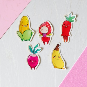 Op de afbeelding: Vijf kleurrijke cartoon stickers met een banaan, een radijs, een maïskolf, een aardbei en een rode paprika. Elke sticker heeft een schattig gezicht en is perfect om een vleugje whimsy toe te voegen aan je planner, laptop of waterfles.