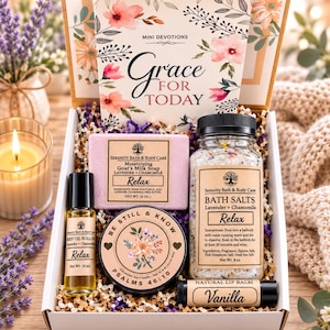 May include: A gift box containing a book titled Grace for Today, a 4 oz bar of lavender and chamomile goat's milk soap, an 8 oz jar of bath salts, a 10 mL body oil roll-on, a soy candle labeled Be Still & Know, and a vanilla lip balm.