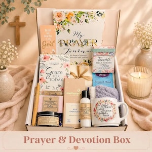May include: A gift box containing a prayer journal, a book titled Grace for Today, a box of Bible verses, a mug with floral text, a Moonstruck milk chocolate bar, a bottle of body lotion, a lavender candle, a soap bar, a lip balm, and a pen.