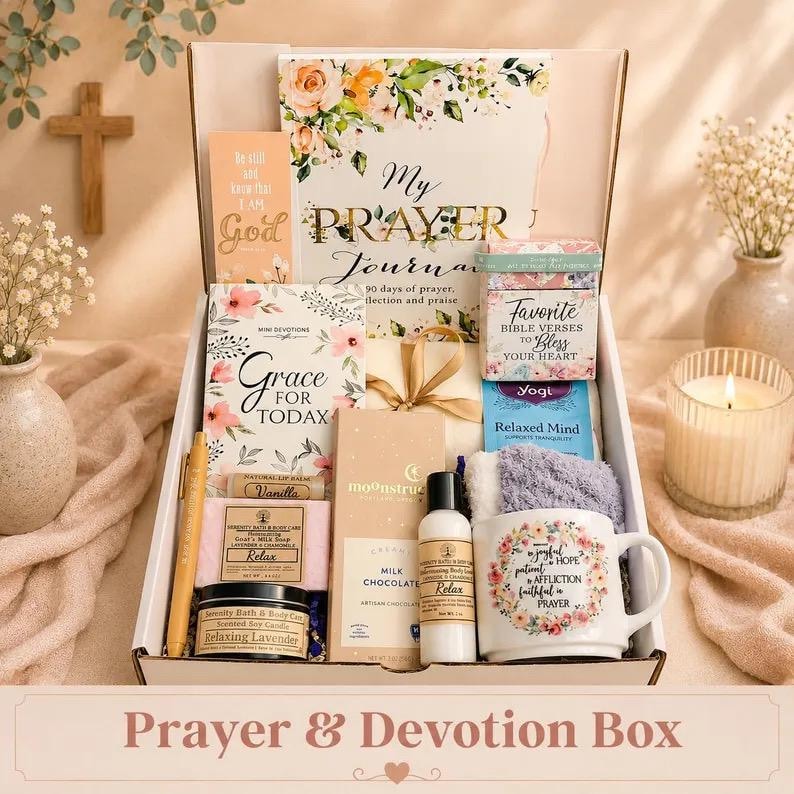 May include: A gift box containing a prayer journal, a book titled Grace for Today, a box of Bible verses, a mug with floral text, a Moonstruck milk chocolate bar, a bottle of body lotion, a lavender candle, a soap bar, a lip balm, and a pen.