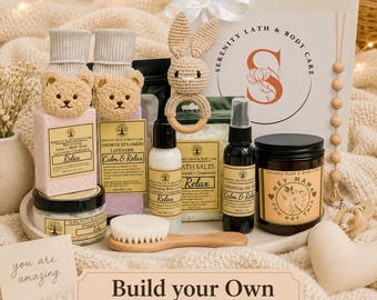 May include: A gift box set labeled Serenity Bath & Body Care containing goat's milk soap, shower steamers, body lotion, bath salts, essential oil mist, a candle labeled Hey Mama You Got This, a crochet bunny rattle, and a wooden brush.