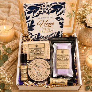 May include: A gift box containing a Mini Devotions Hope for Today book, a 4 oz bar of Serenity Bath & Body Care goat's milk soap, a 3 oz lavender shower steamer, a body oil roller, a Be Still & Know candle, and a vanilla lip balm in a box.