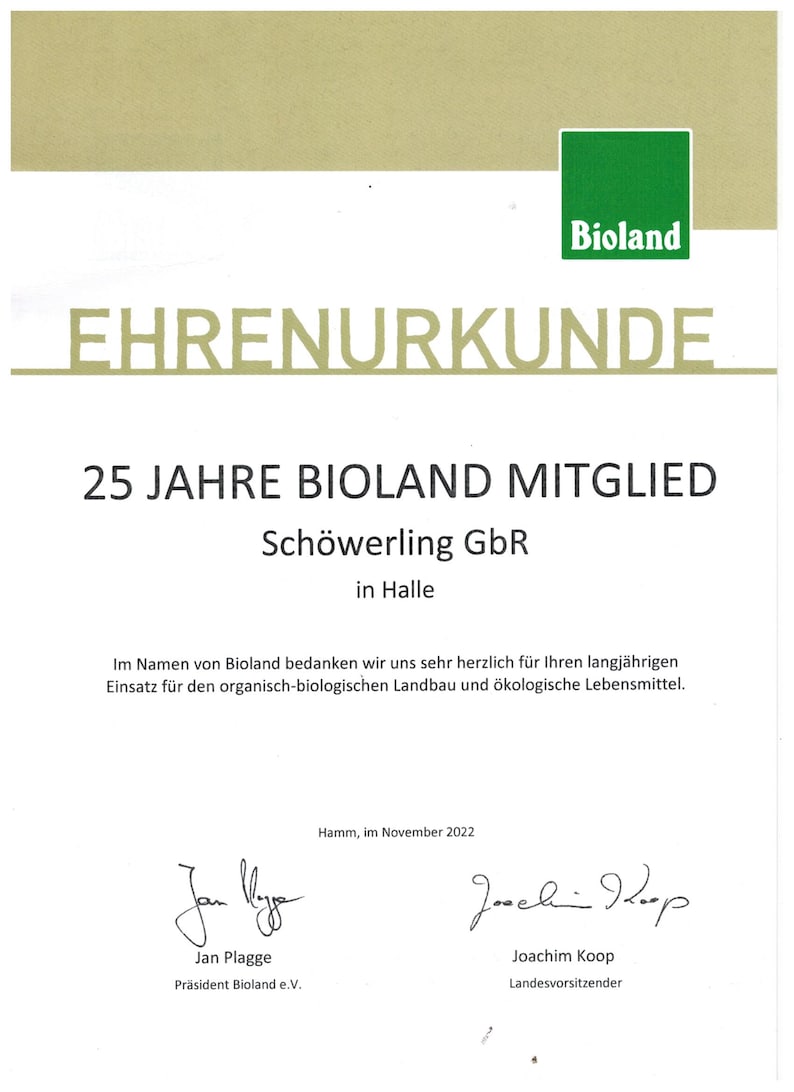 May include: A certificate of honor from Bioland, a German organic farming association, recognizing Sch&ouml;werling GbR for 25 years of membership. The certificate is printed on white paper with green and gold accents. It features the Bioland logo and the text "Ehrenurkunde" in gold lettering.