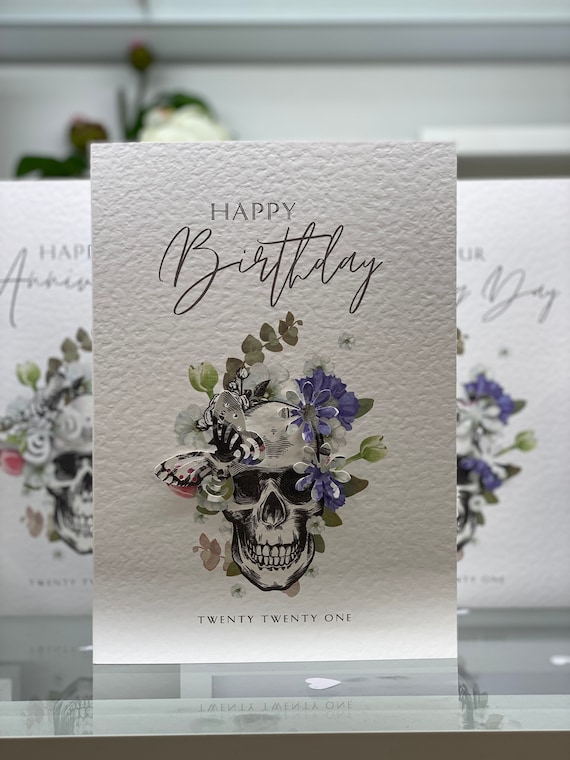 A gothic-meets-whimsical birthday card combining skulls, botanicals, and butterflies — intricate enough to be framed, dark enough to be genuinely different.