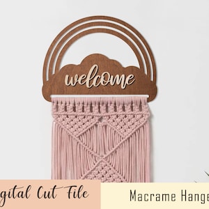 May include: A wooden rainbow and cloud cutout with the word "welcome" on it. A pink macrame hanger is hanging from the cutout.