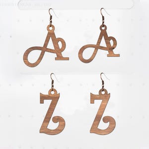 May include: Four wooden earrings, two with the letter "A" and two with the letter "Z". The earrings are a light brown colour and have a hook for the ear. The letters are in a cursive font.