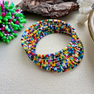 May include: A multi-strand coil bracelet constructed from numerous small, round glass seed beads in a vibrant array of colors including red, yellow, blue, green, orange, purple, white, and black, arranged in a repeating, randomized pattern.