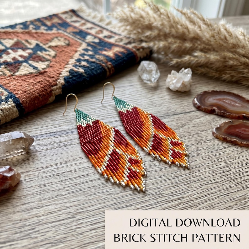 May include: A pair of long, leaf-shaped beaded earrings featuring a gradient pattern of deep red, bright orange, and teal green glass beads. The earrings are constructed with a brick stitch technique and hang from gold-toned metal ear wires.
