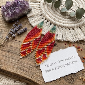 May include: A pair of long, leaf-shaped beaded earrings featuring a gradient pattern of teal, orange, red, and yellow beads. A white paper note with the text DIGITAL DOWNLOAD, BRICK STITCH PATTERN is placed next to the earrings on a wooden surface.