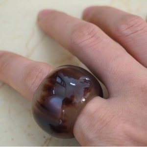 Könnte beinhalten: Ein großer, runder Ring aus Harz mit glänzender Oberfläche. Der Ring ist braun mit einem marmorierten Muster.