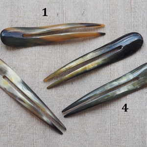 May include: Four brown and black horn hair combs with two prongs. The combs are numbered 1 through 4.