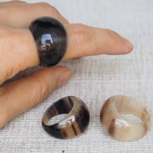 Puede incluir: Tres anillos hechos de cuerno, uno negro y dos con rayas marrones y blancas.