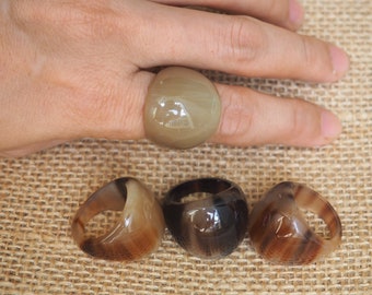 以下が含まれることがあります： 茶色と黒の角のリングが4つ。リングはすべて茶色と黒の異なる色合いです。リングはすべて楕円形で、滑らかな仕上がりです。