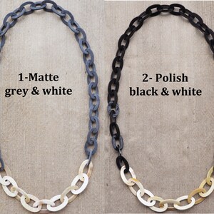 May include: Two necklaces with chain links. One is matte grey and white, the other is polished black and white. The text on the image reads "1-Matte grey & white" and "2- Polish black & white".