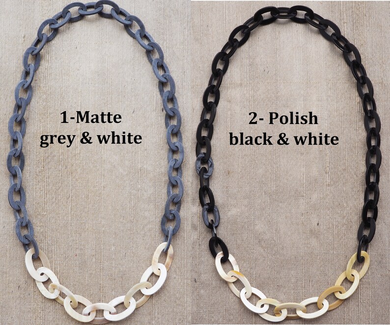 May include: Two necklaces with chain links. One is matte grey and white, the other is polished black and white. The text on the image reads "1-Matte grey & white" and "2- Polish black & white".