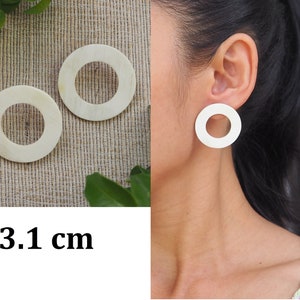May include: A pair of white, round earrings with a 3.1 cm diameter. The earrings are made of a smooth, white material and have a simple, modern design.