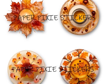 May include: Four decorative candle holders with autumn-themed designs. Each holder features a round, clear glass base with a candle in the centre. The designs include a wreath of autumn leaves, a wreath of autumn leaves and berries, a single autumn leaf, and a wreath of autumn leaves and berries.