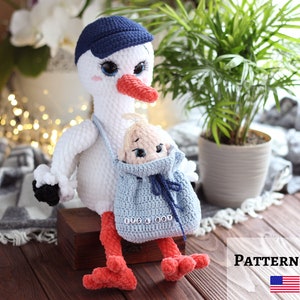 Puede incluir: Una cigüeña blanca de crochet con una gorra de béisbol azul lleva un muñeco de bebé en una bolsa de crochet azul con el texto "It's a Boy".