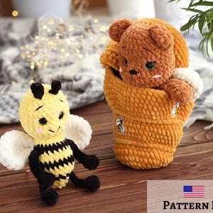 May include: A crocheted bee plush toy with yellow and black stripes and white wings sits on a wooden surface. A crocheted brown bear plush toy is inside a crocheted honey pot with a yellow and black bee design. The text "PATTERN PDF" is on the bottom of the image.