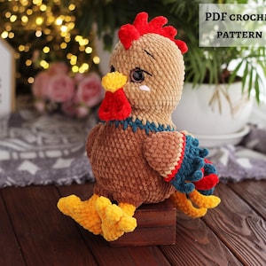 May include: A handmade crochet rooster in brown, red, yellow, and blue. The rooster has a red comb, yellow feet, and a blue and red wing. The text "PDF CROCHET PATTERN" is displayed with the American flag.