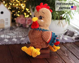 May include: A handmade crochet rooster in brown, red, yellow, and blue. The rooster has a red comb, yellow feet, and a blue and red wing. The text "PDF CROCHET PATTERN" is displayed with the American flag.