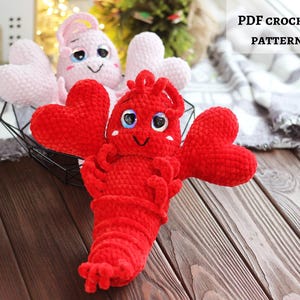 Puede incluir: Una langosta roja de ganchillo con pinzas en forma de corazón y una cara sonriente. La imagen también presenta un pulpo rosa con tentáculos en forma de corazón. El texto de la imagen dice "PDF CROCHET PATTERN".