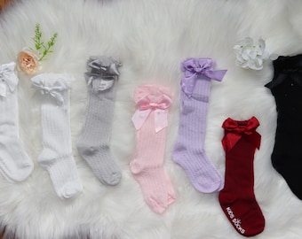 May include: Set of ten knee-high socks with a satin bow at the top. The socks are in various colors, including white, gray, pink, lavender, red, and black.