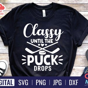 May include: Black t-shirt with white text that reads "Classy Until The Puck Drops". The text is surrounded by two hockey sticks and a puck.