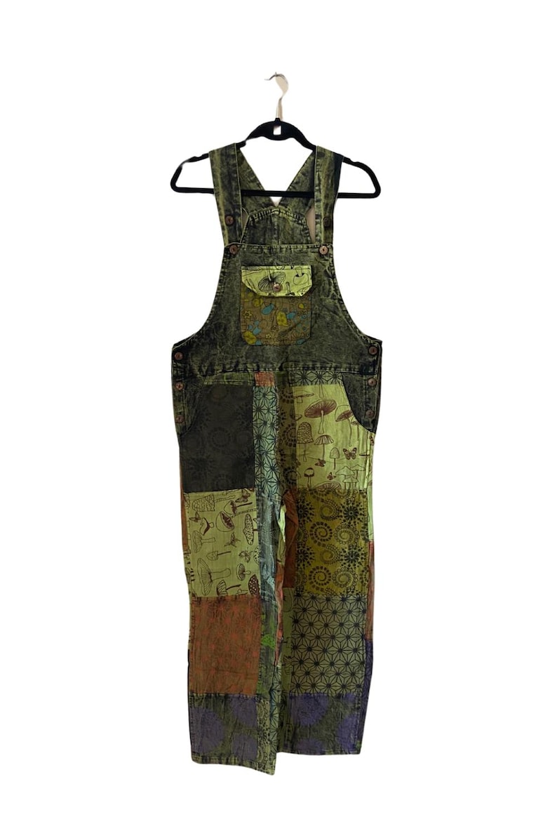 May include: Green patchwork denim dungarees with a variety of printed designs, including mushrooms and flowers.